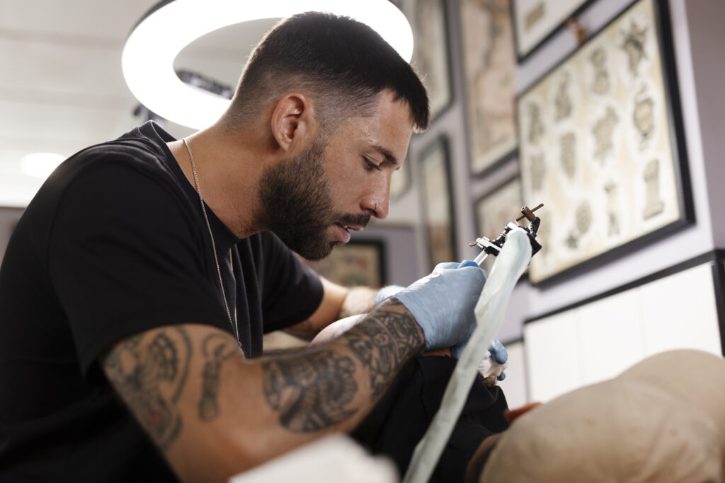 talented tattoo artist doing his job side view
